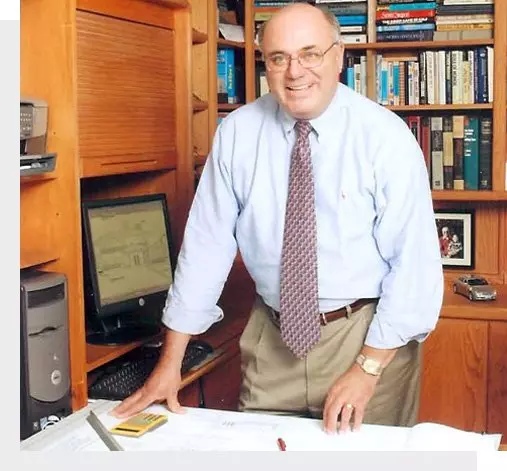 A man standing in front of a desk with papers on it.